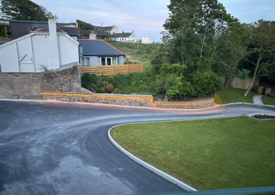 Warm lighting follows the curve of a driveway wall.