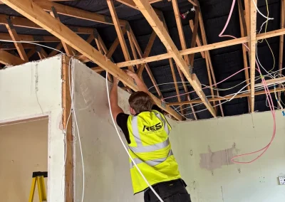 An RES electrician installing wiring above the ceiling.