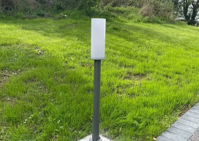 A garden bollard light beside a paved path.