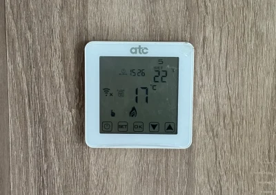 A wall-mounted digital heating thermostat.