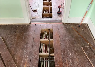 Floorboards lifted to access wiring during a rewire.